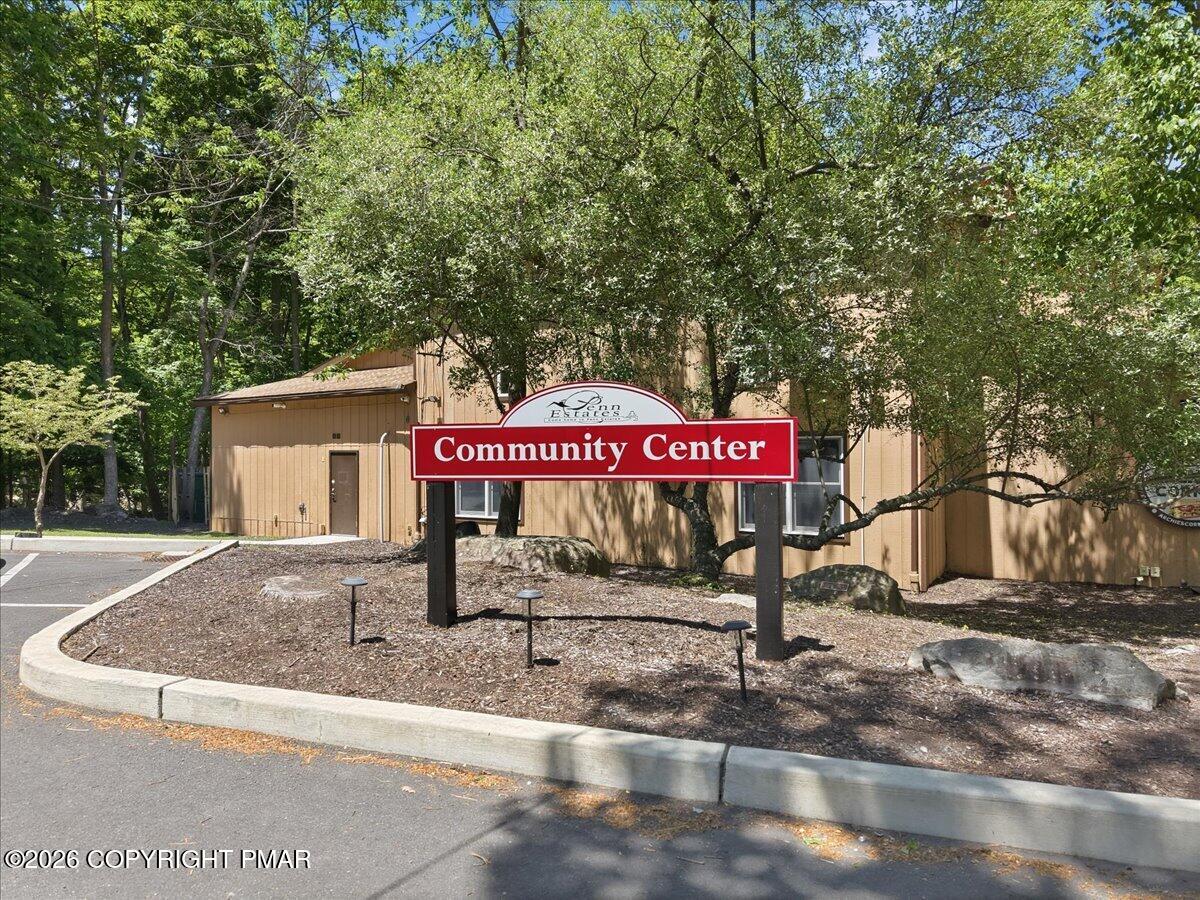 Penn Estates community center behind a red Community Center sign, shaded by mature trees.