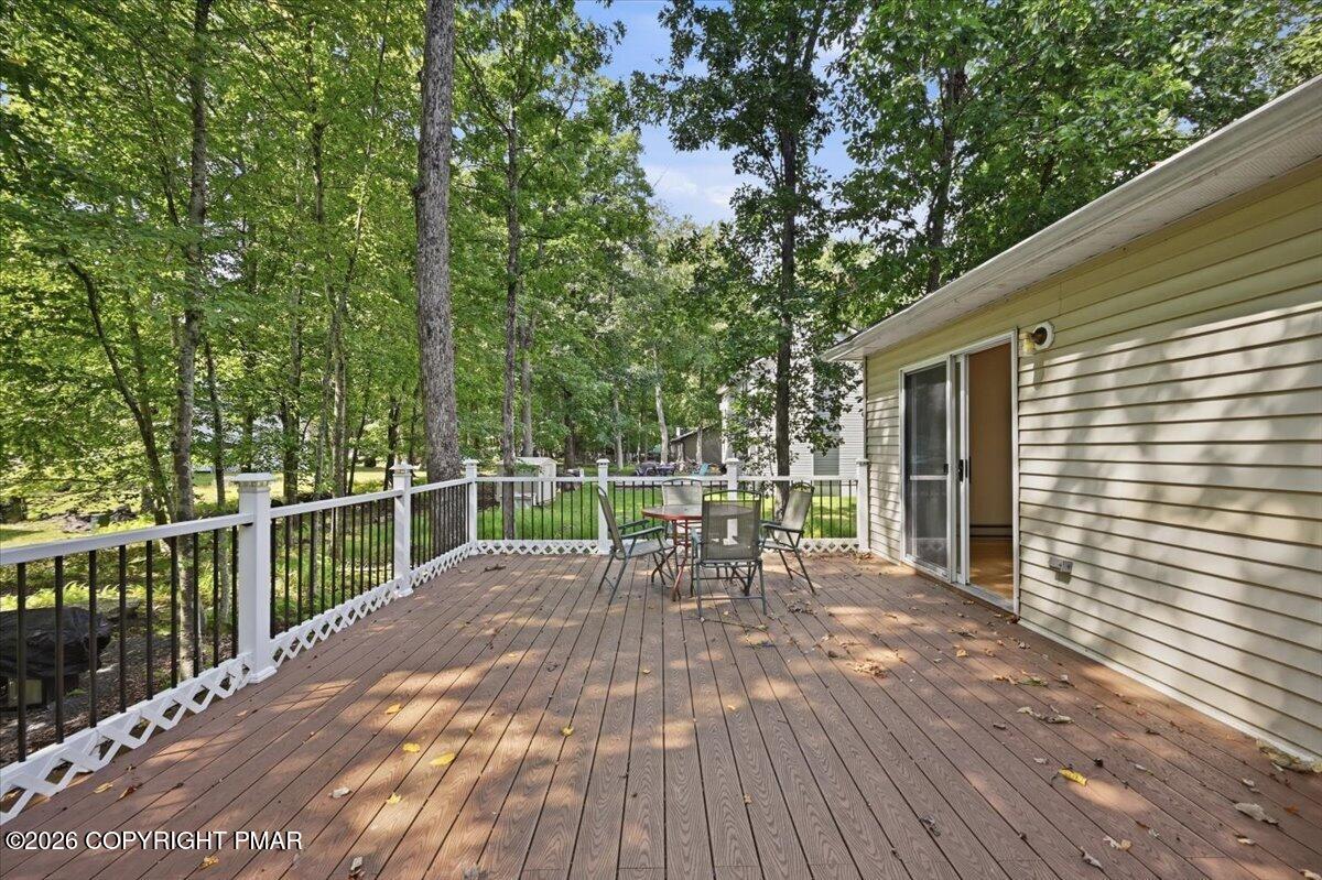 Wood deck with outdoor seating, black railings, and a view of the wooded yard.