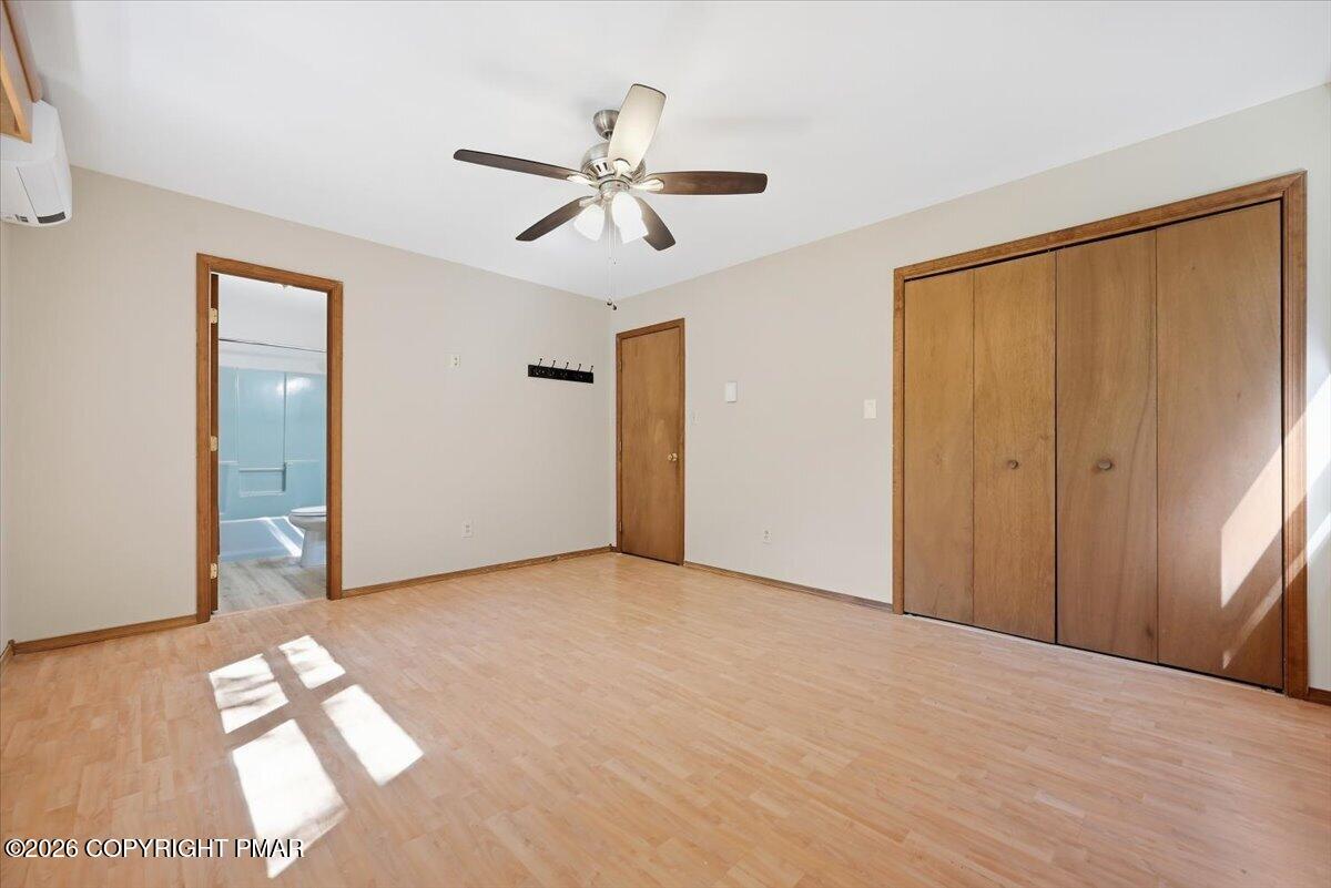 Unfurnished bedroom with light wood flooring, a ceiling fan, and large wooden closet.