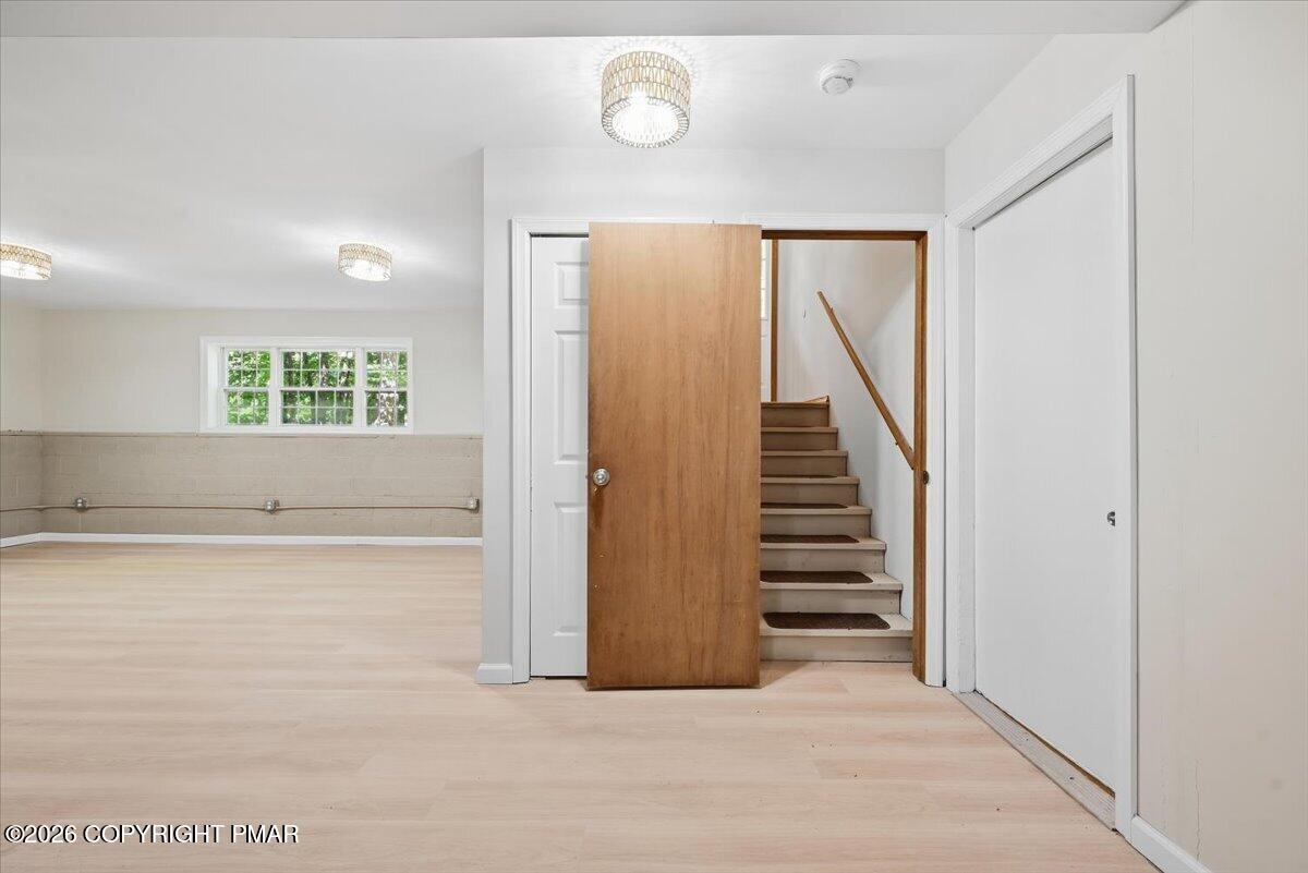 Vacant room with light flooring and tiled lower walls, opening to a staircase.
