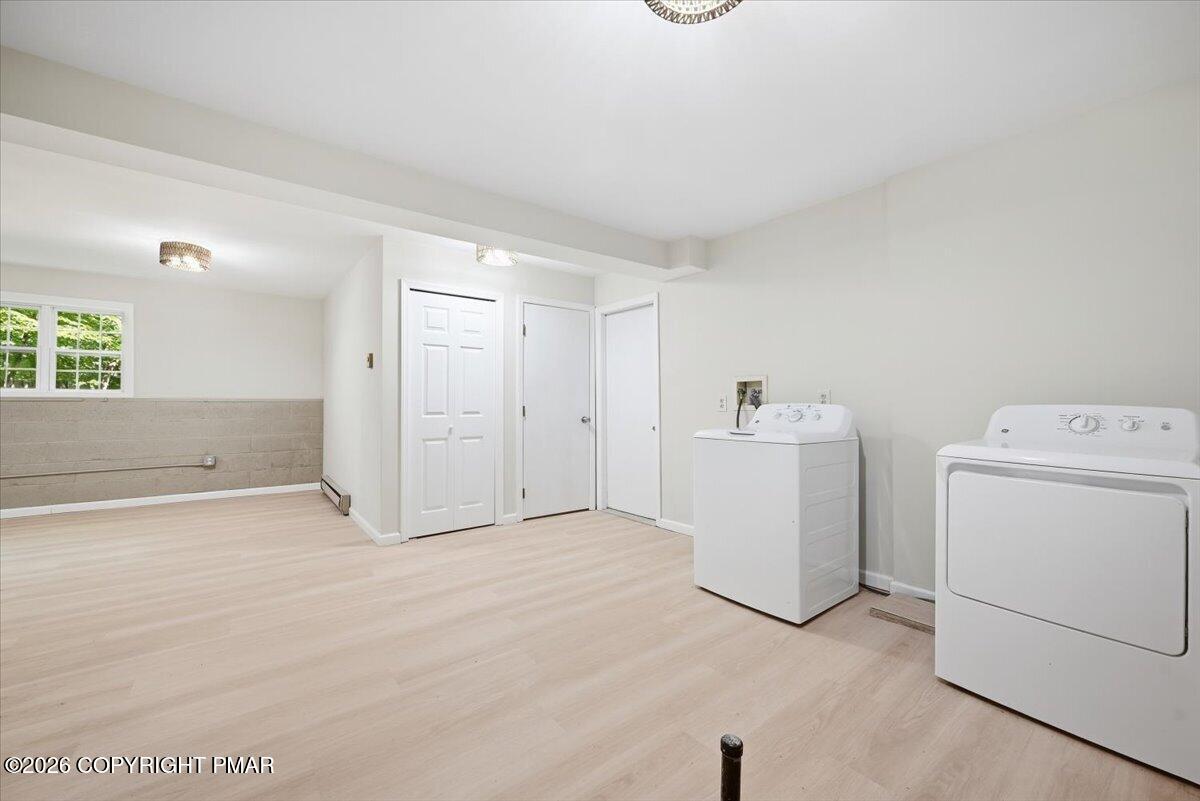 Laundry room with white washer and dryer, light flooring, and a small window.