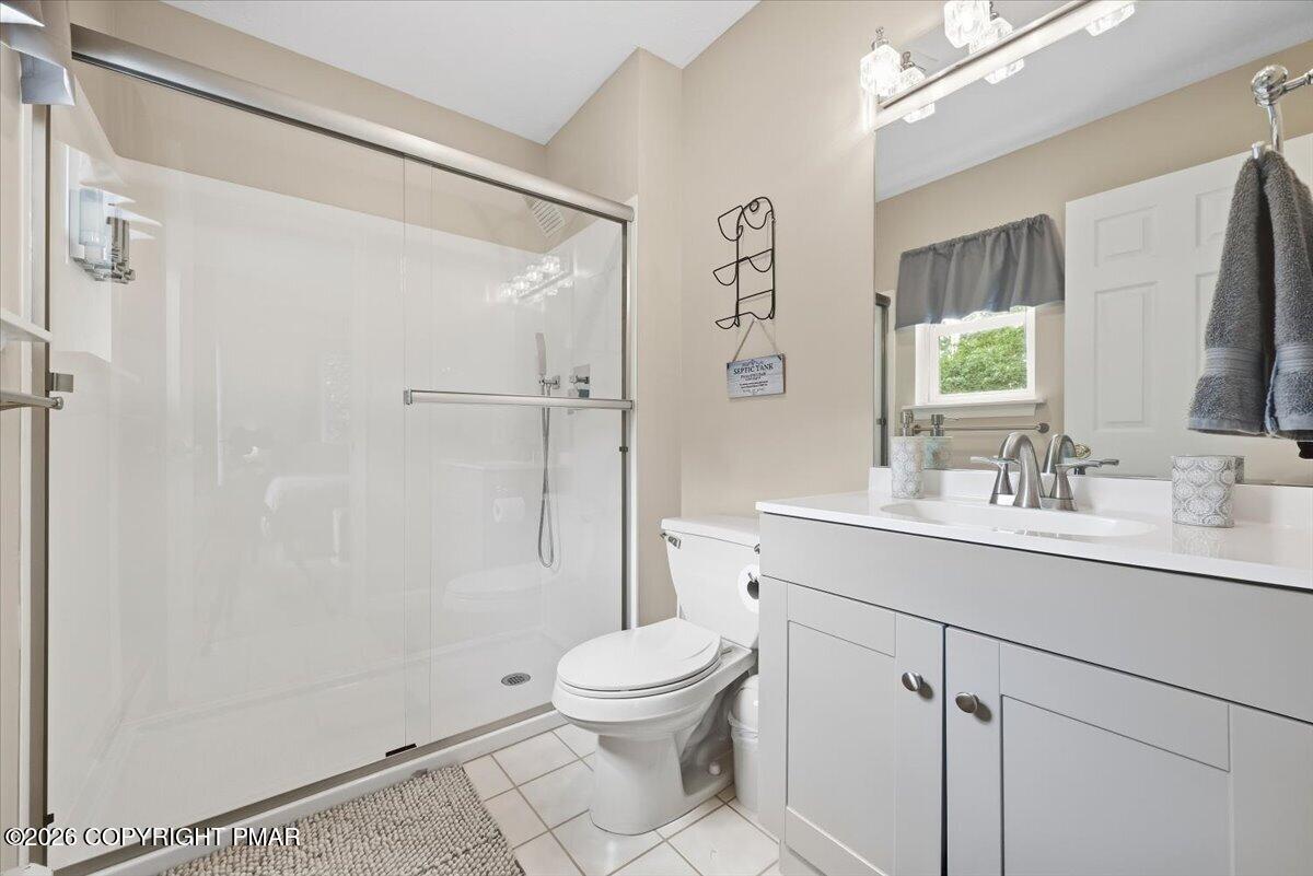 Bathroom with a glass-enclosed shower, white vanity, and toilet.
