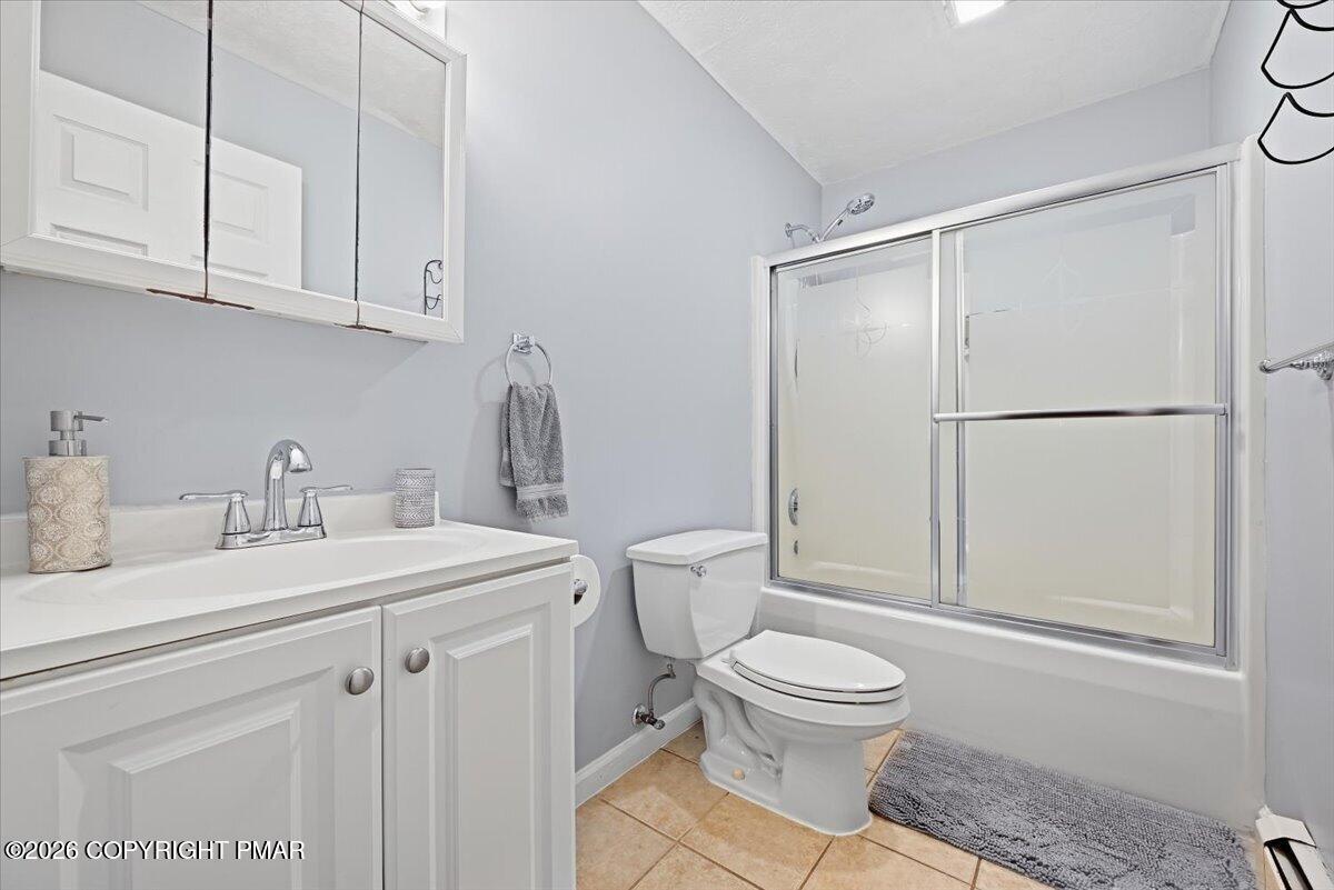 Bathroom with a white vanity, mirrored cabinet, and sliding glass tub-shower enclosure.