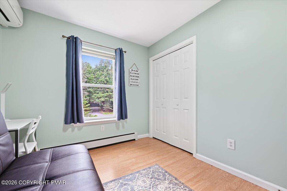 Furnished room with pale green walls, blue curtains, white closet doors, and a window overlooking trees.