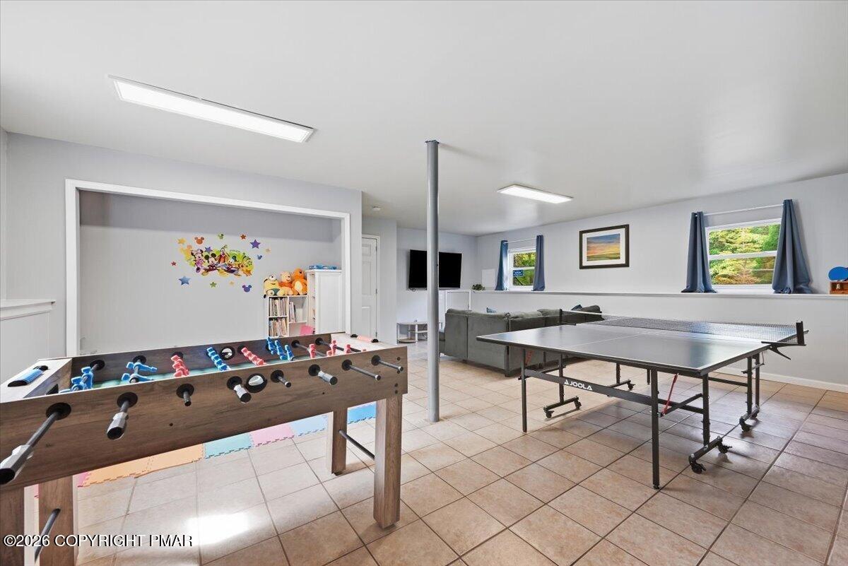 Recreation room with foosball and ping-pong tables, a sofa, and a children's play nook.