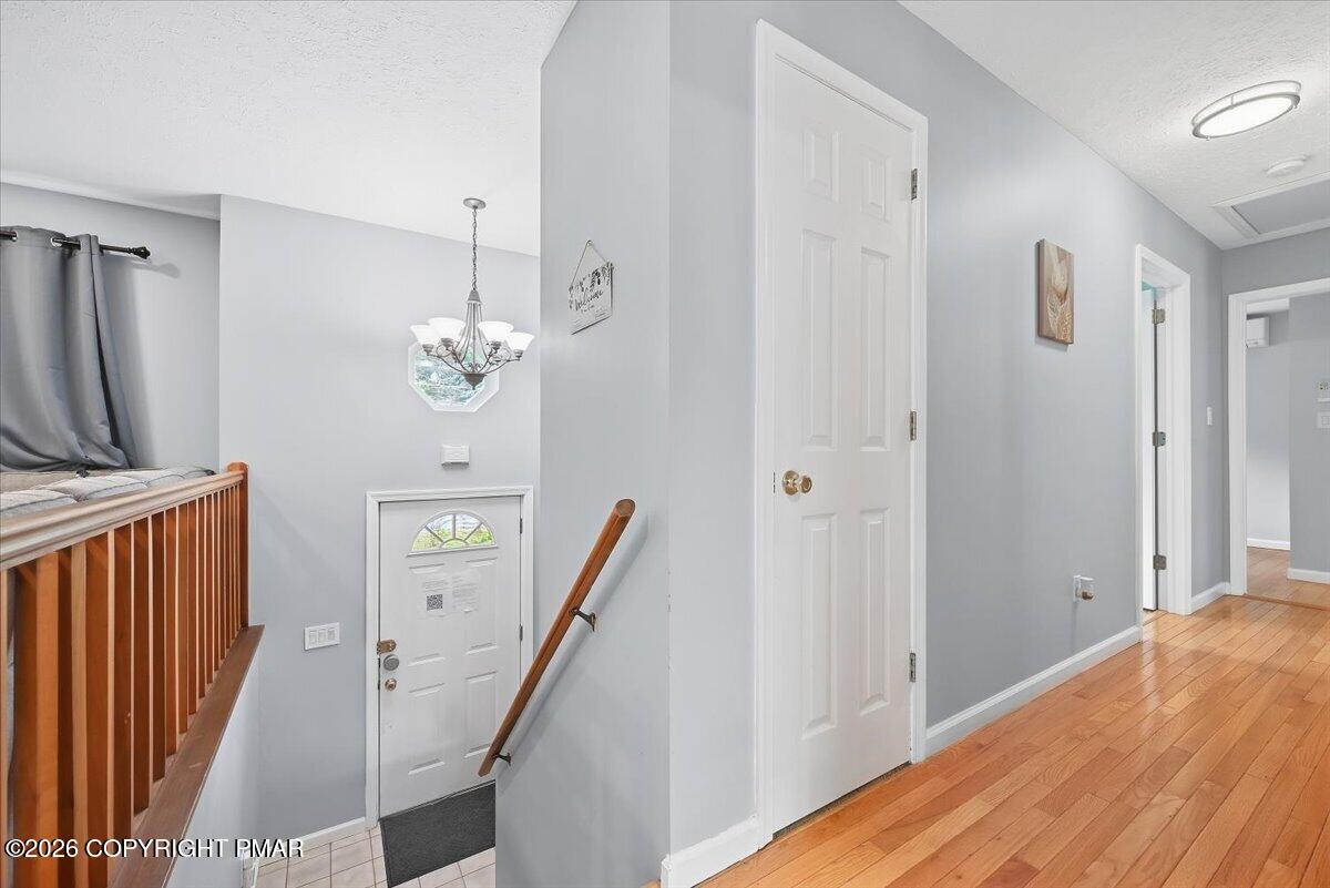 Entry hall with hardwood floors, a white front door, and a wooden stair railing.