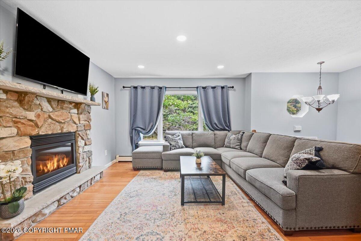 Living room with a stone fireplace, mounted television, and gray sectional sofa.