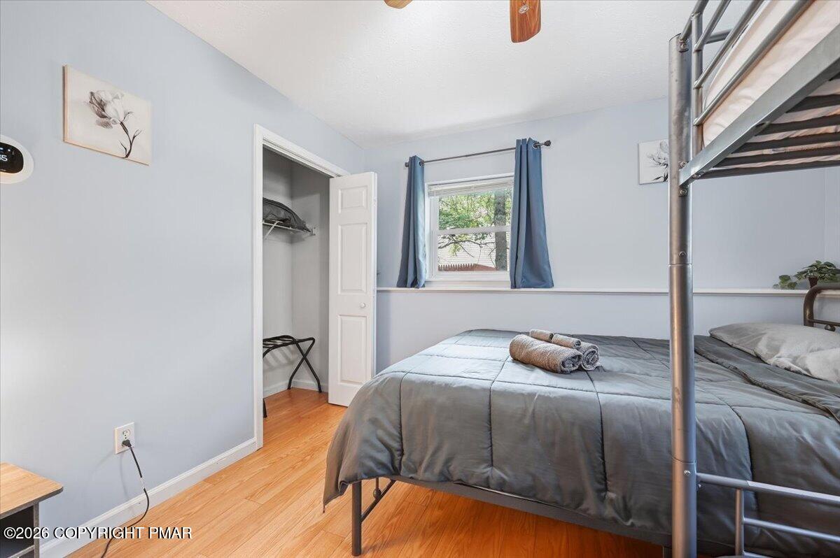 Bedroom with a metal bunk bed, gray bedding, blue curtains, and warm wood flooring.