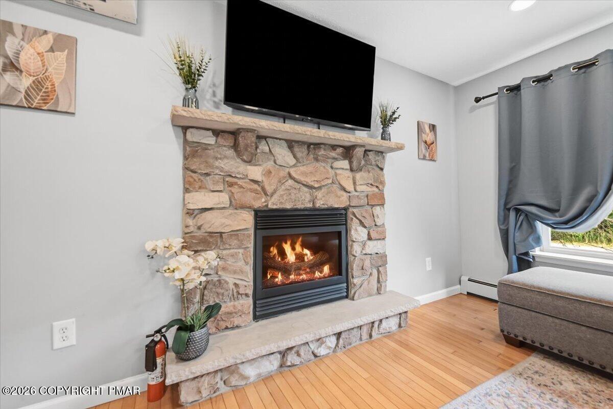 Stone-surround living room fireplace with a lit fire and wall-mounted television.