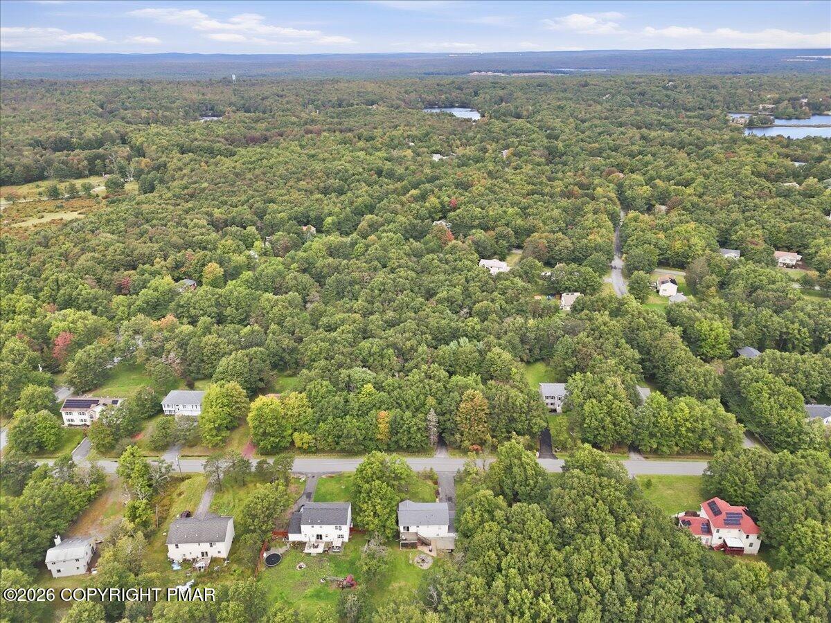 Aerial view of homes among dense woodland, with lakes visible in the distance.
