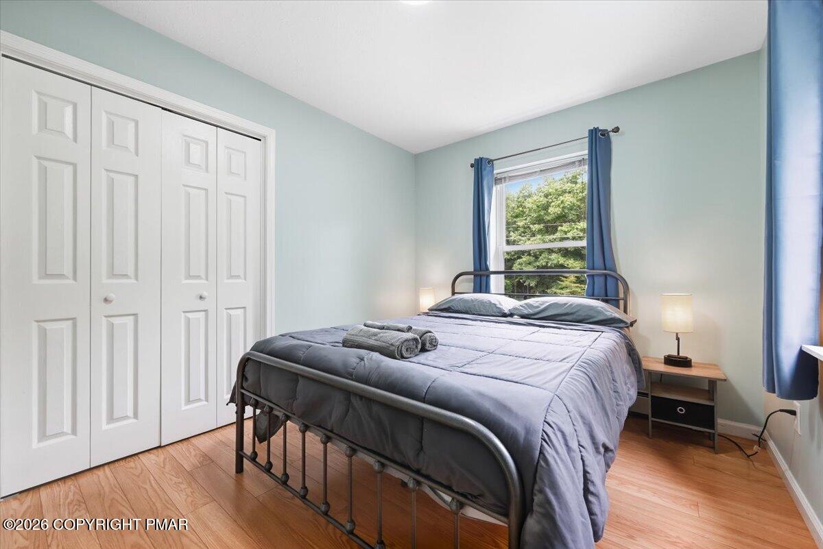 Bedroom with a gray metal bed, white closet doors, and blue curtains beside a window.