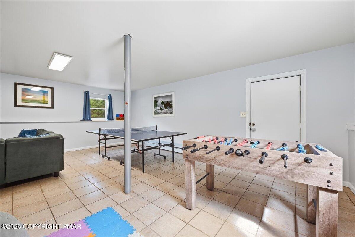 Recreation room with foosball and ping-pong tables and a sofa.