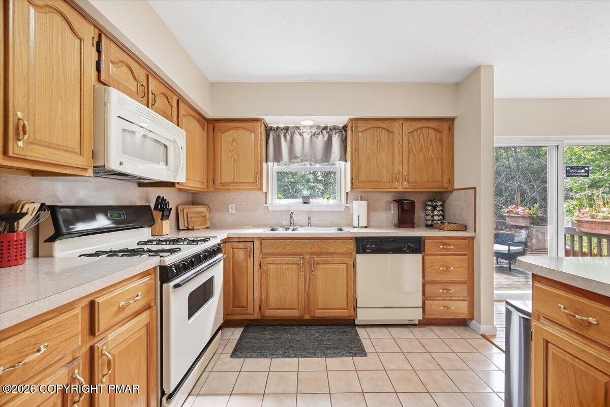 Kitchen with honey-colored cabinets, gas range, and sliding doors opening to a deck.