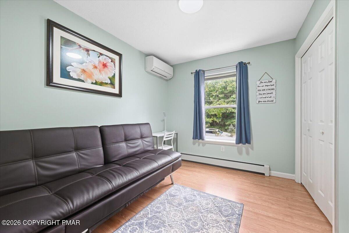 Sitting room with a dark leather sofa, pale green walls, and blue curtains beside the window.