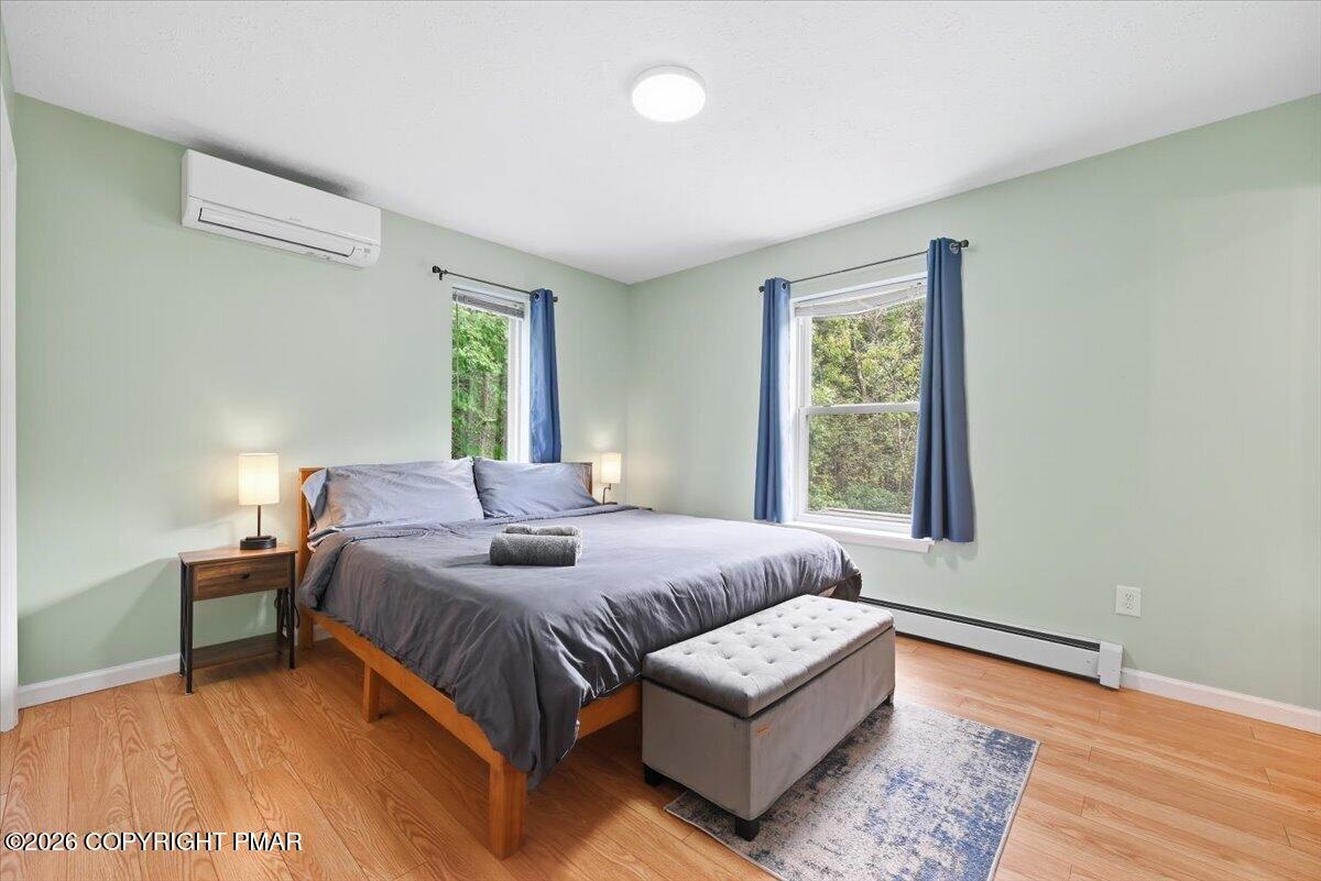 Bedroom with a gray king-size bed, tufted bench, blue curtains, and pale green walls.