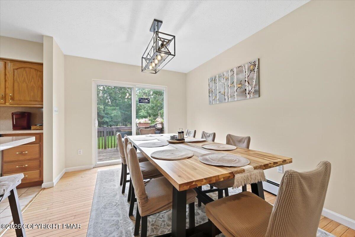 Dining room with a long wooden table and sliding glass doors opening to a deck.
