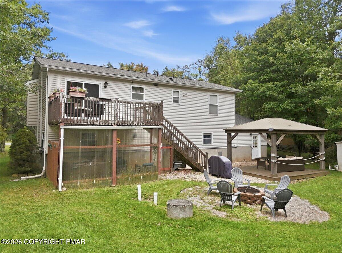 Rear of a two-story home with a raised deck, gazebo, and fire pit patio.