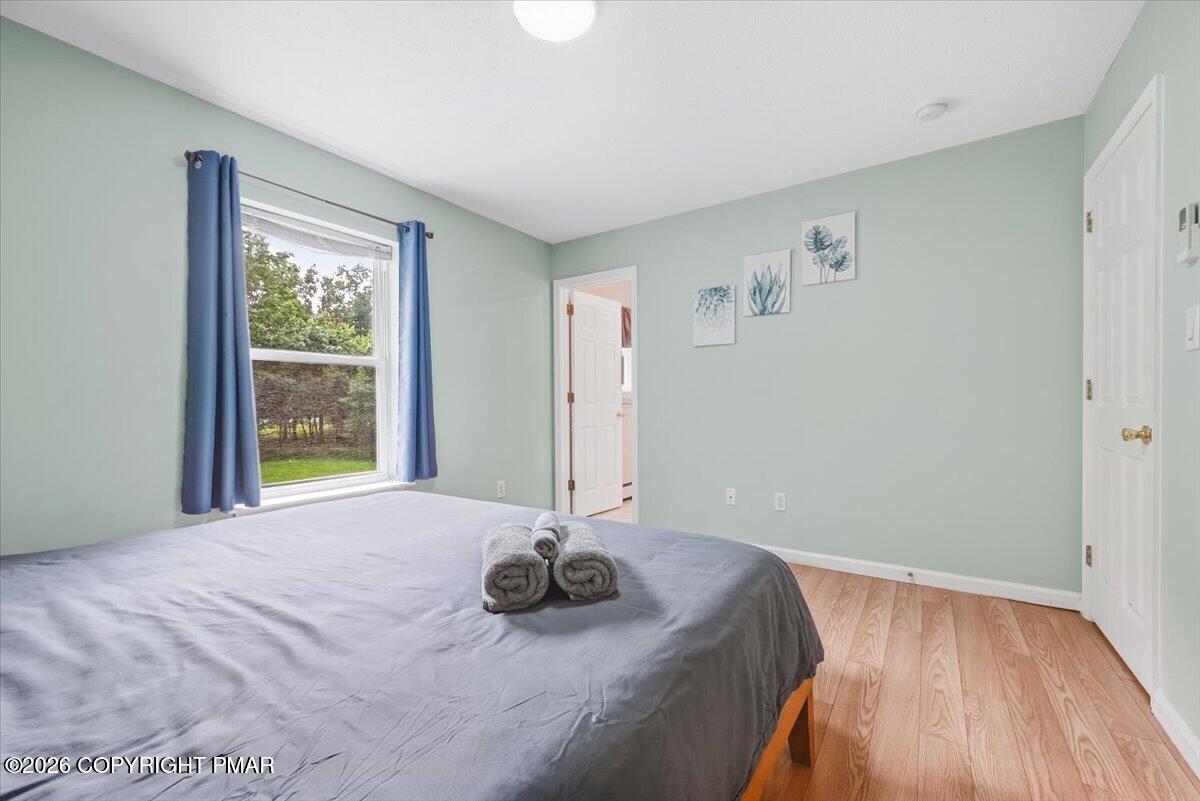 Bedroom with a gray-covered bed, blue curtains, and a window overlooking trees.