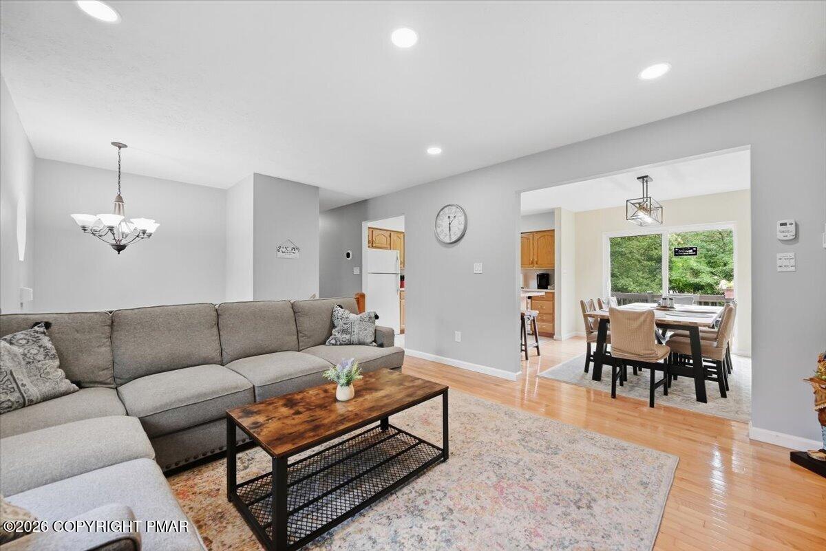 Living room with a gray sectional and wood coffee table, open to a dining area beside a large window.
