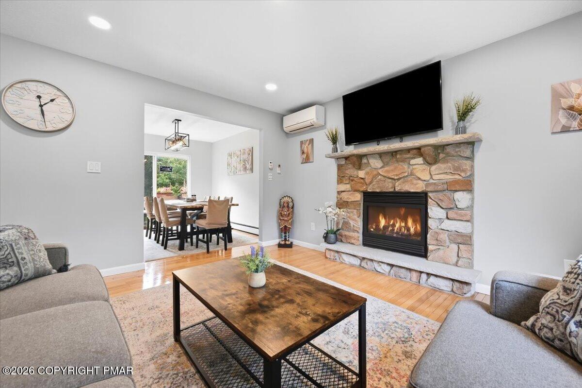 Living room with a stone fireplace, mounted television, and view into the dining room.