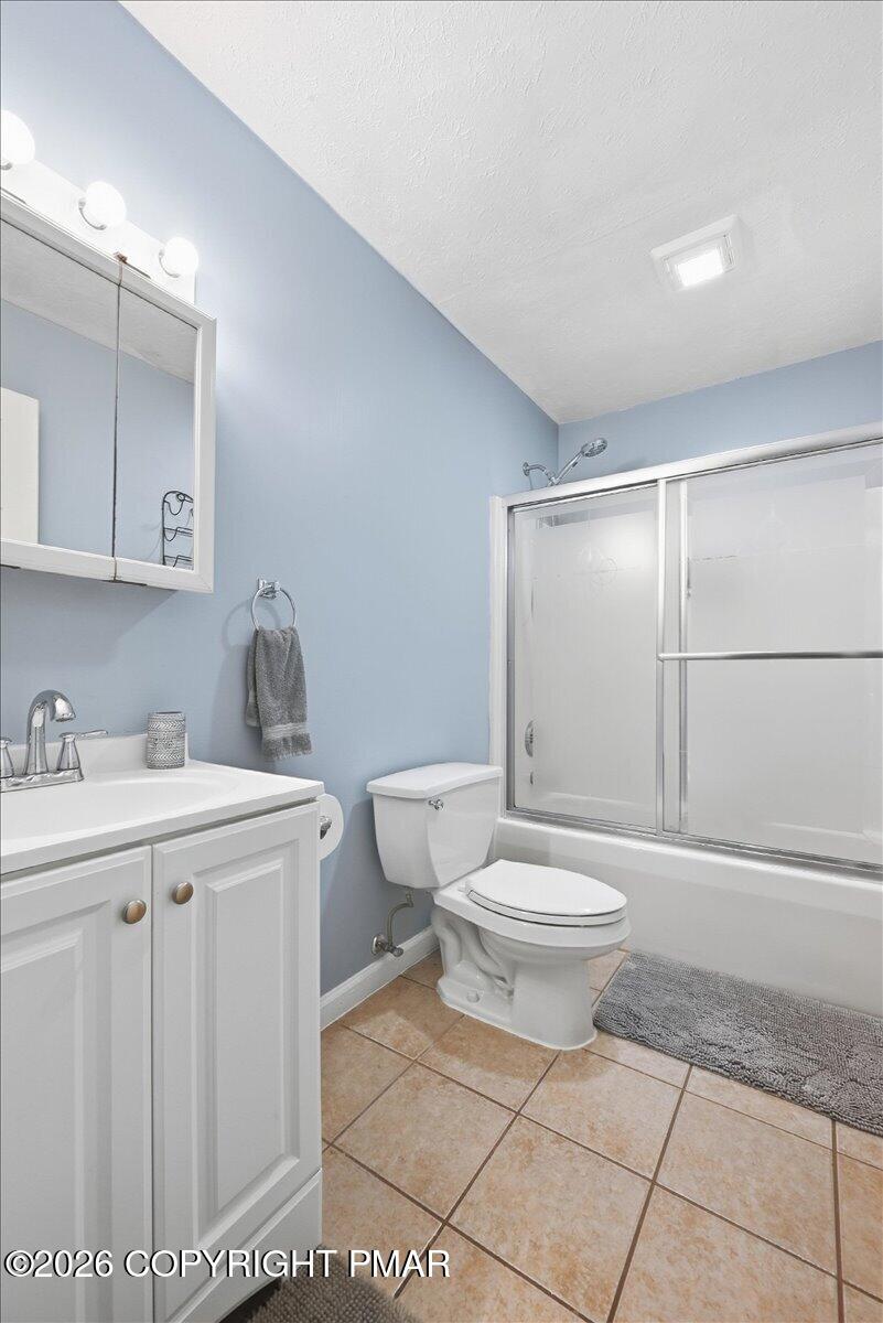 Bathroom with a white vanity, toilet, and tub-shower against pale blue walls.