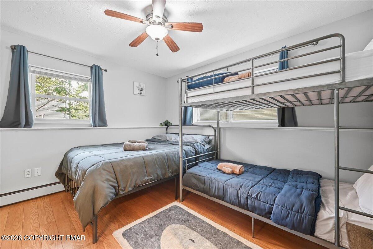 Bedroom with a metal bunk bed, a separate bed, and hardwood floors.