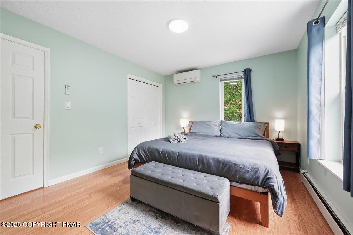 Bedroom with a large bed, gray bench, pale mint walls, and blue curtains beside a window.