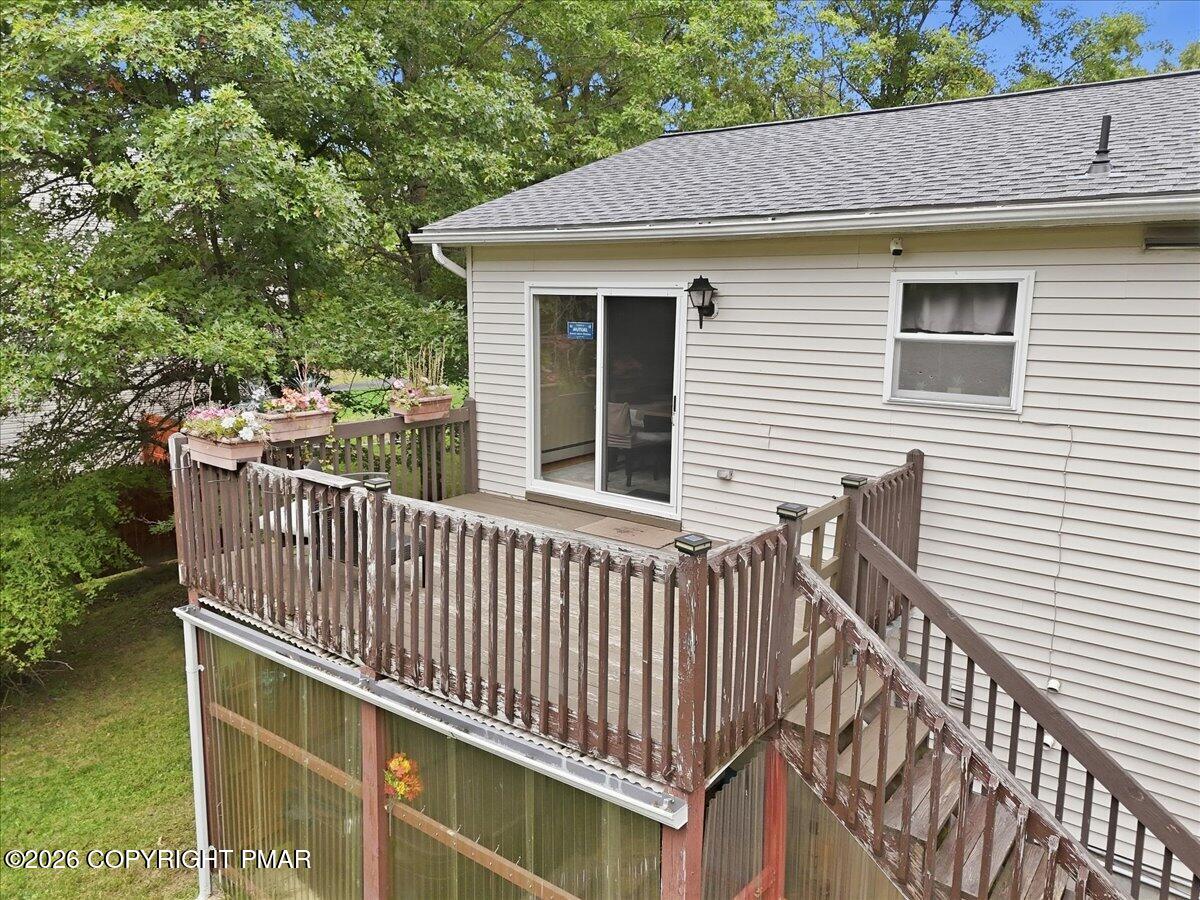 House exterior with a wooden deck, flower boxes, and stairs above an enclosed porch.