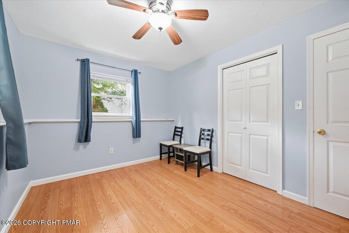 Pale blue room with wood flooring, blue curtains, two chairs, and a double-door closet.