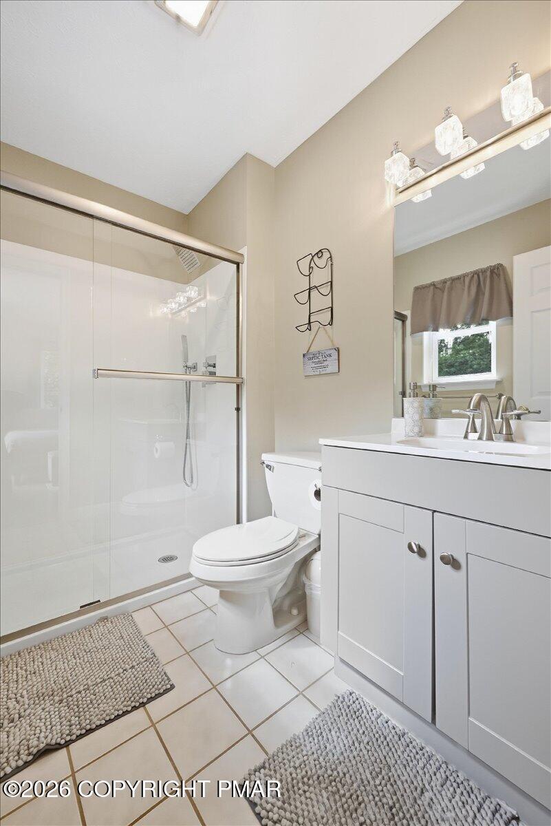 Bathroom with glass-enclosed shower, white vanity, and window with a taupe valance.