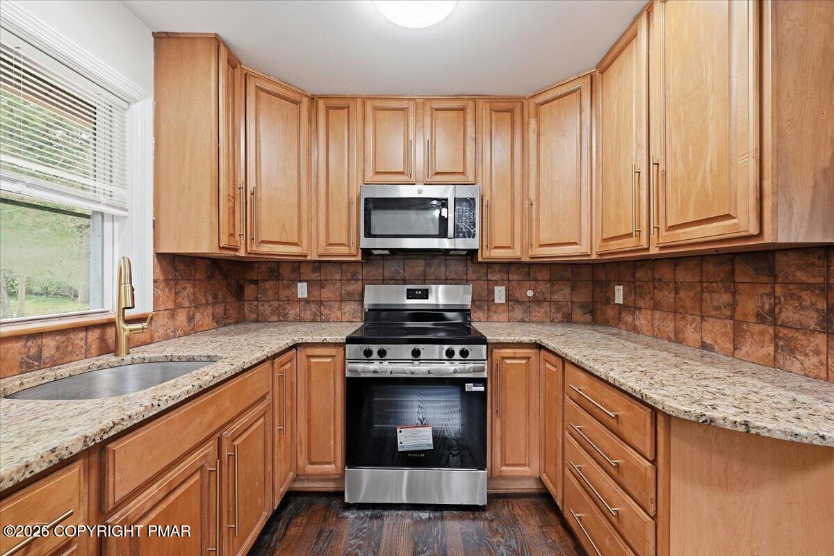 Kitchen with honey-toned cabinets, granite counters, and stainless steel appliances.