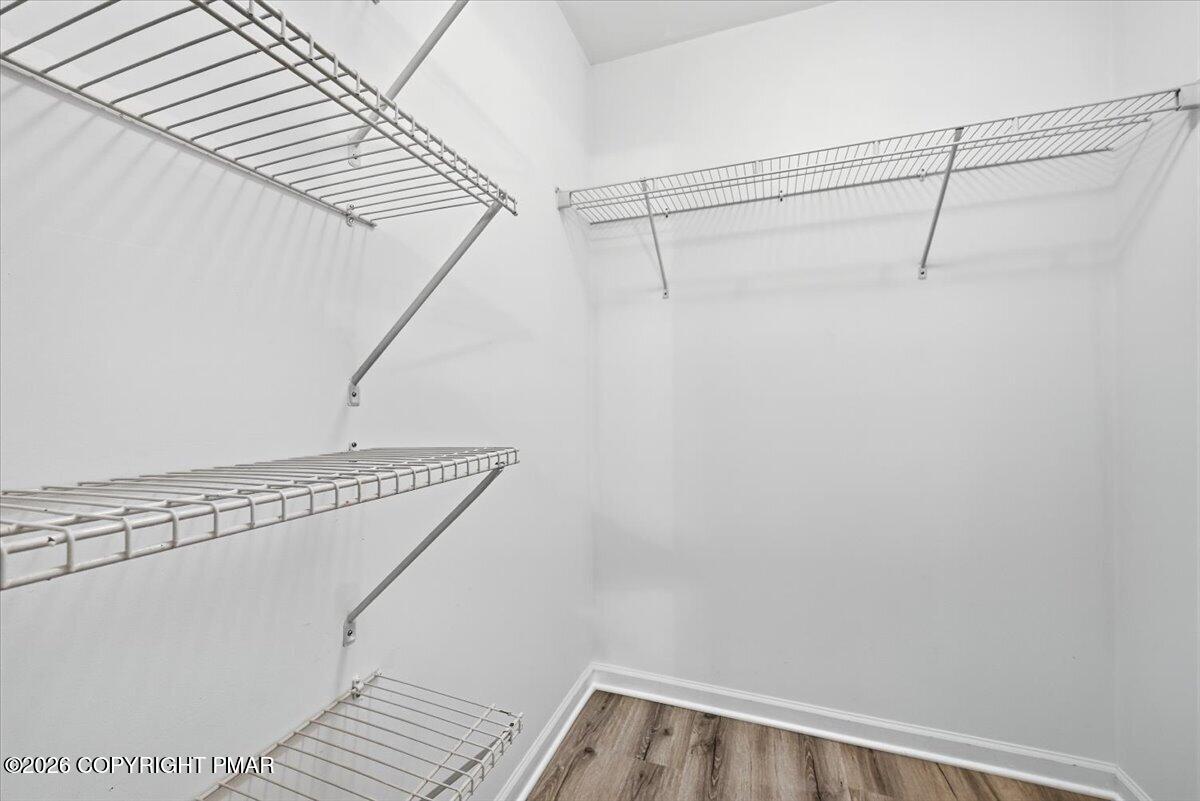 Walk-in closet with wire shelves and wood-look flooring.