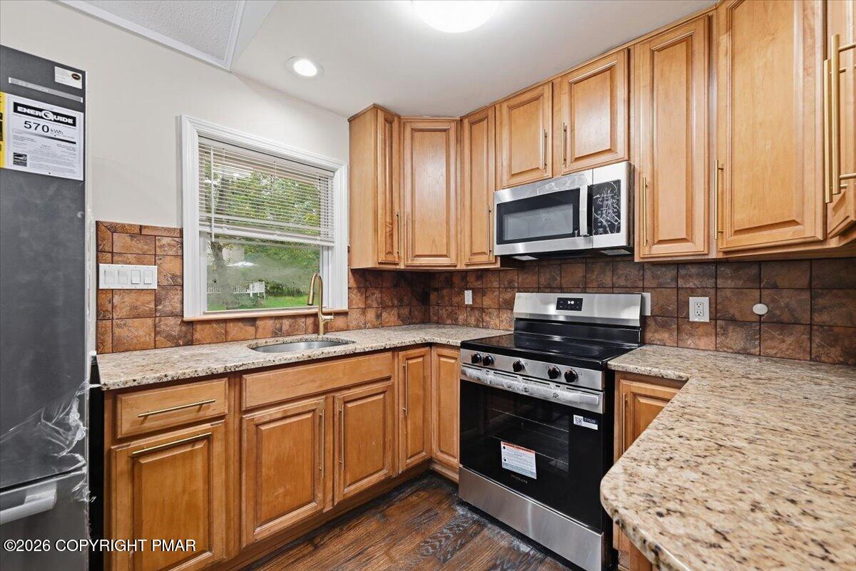 Kitchen with honey-toned wood cabinets, granite counters, and stainless steel appliances.