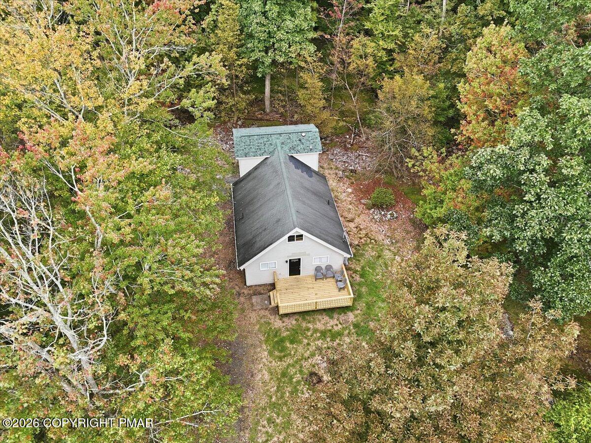 Aerial view of a house and wooden deck surrounded by colorful autumn trees.