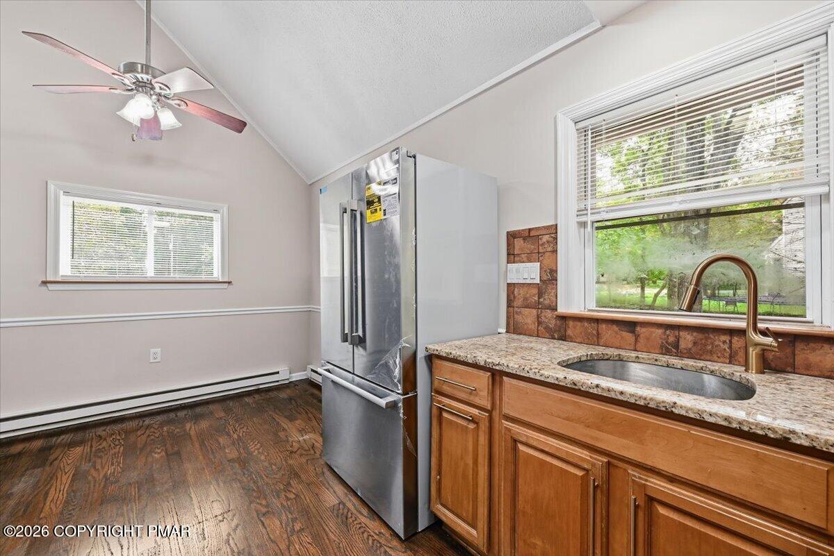 Kitchen with wood cabinets, stainless steel refrigerator, and sink beneath a large window.