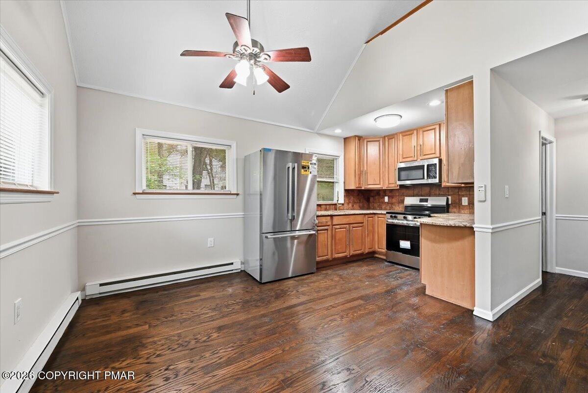 Kitchen with wood cabinets, stainless steel appliances, and dark hardwood floors.