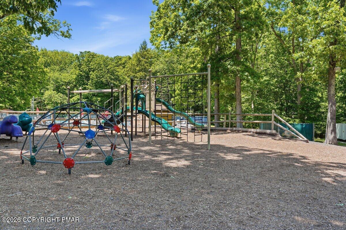 Playground with climbing dome and slides beneath leafy trees.