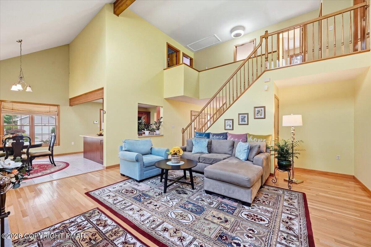 Open living and dining area with a sectional, patterned rugs, and a staircase to an upper landing.