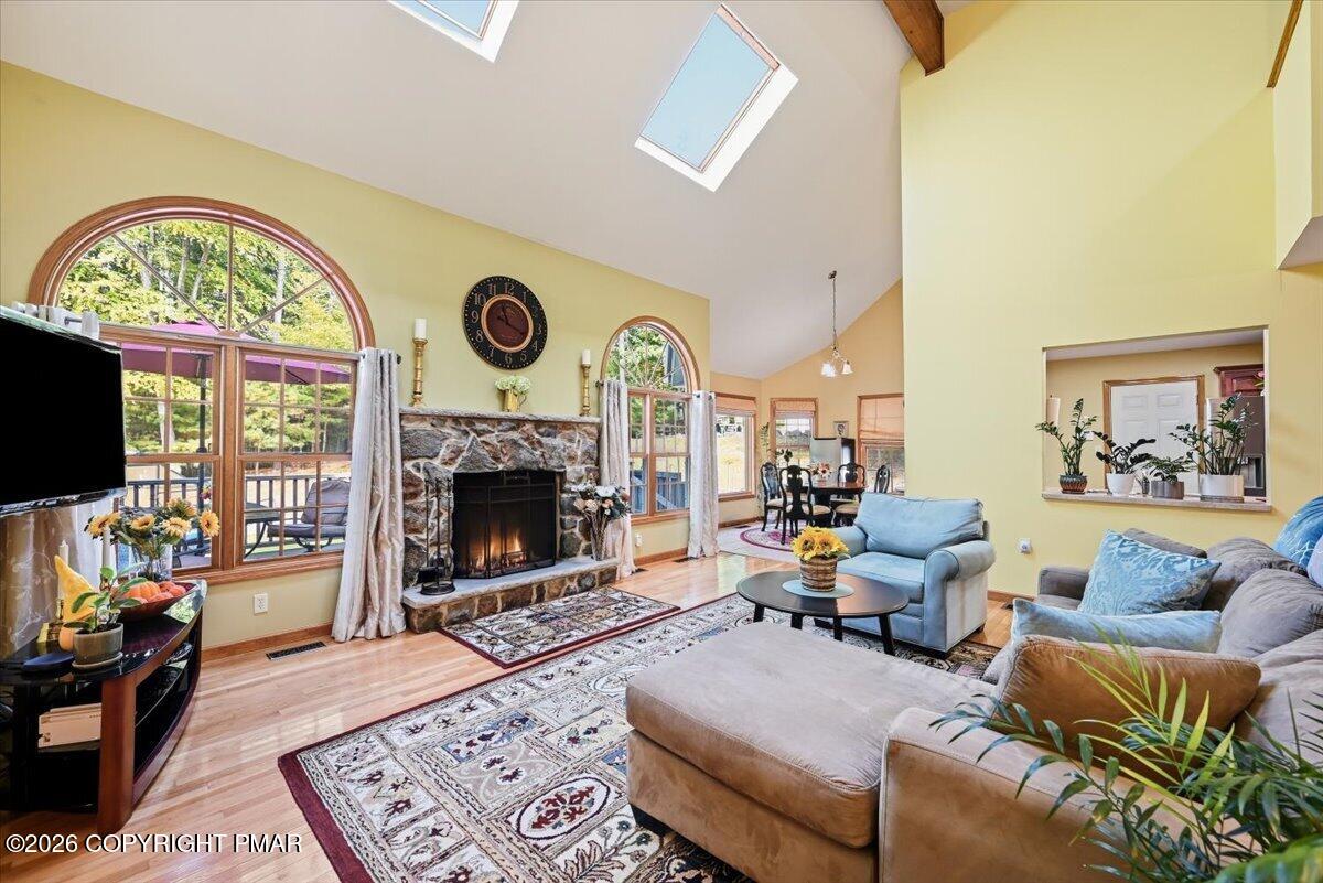 Living room with a stone fireplace, arched windows, vaulted ceiling, and blue and tan seating.