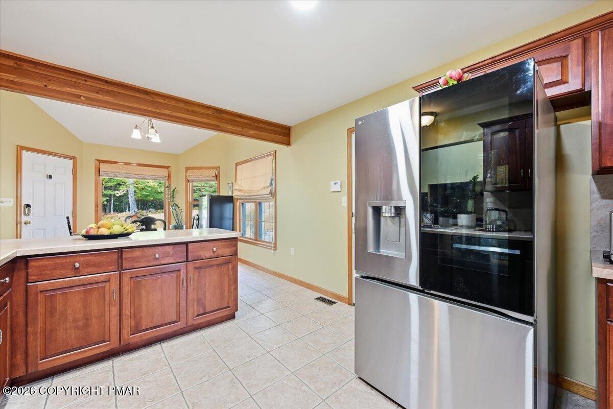 Kitchen with reddish wood cabinetry, a central island, and a large stainless-steel refrigerator.