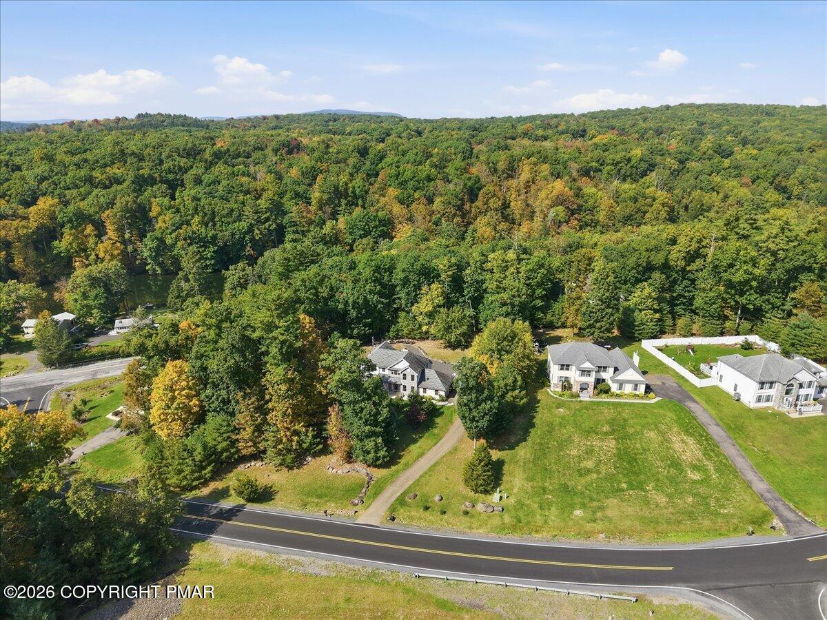 Aerial view of homes beside a road, with wooded hills stretching across the background.