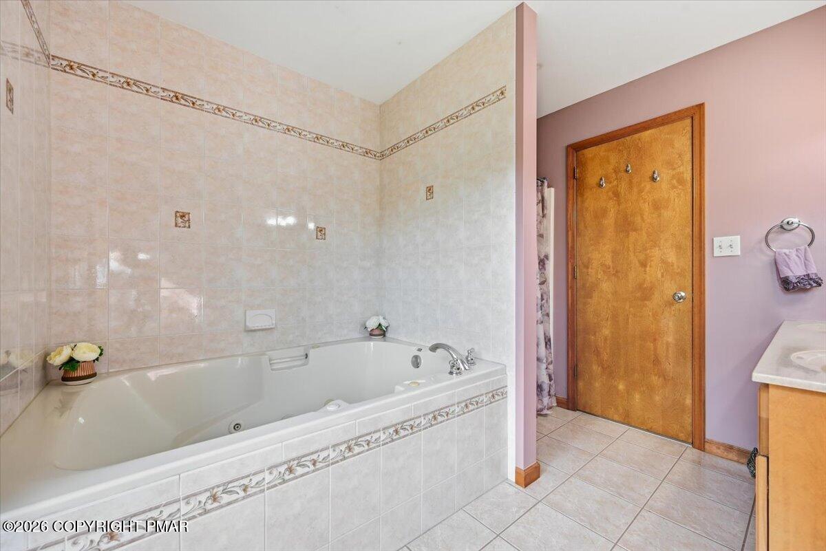 Bathroom with a large tiled jetted tub and decorative tile borders.