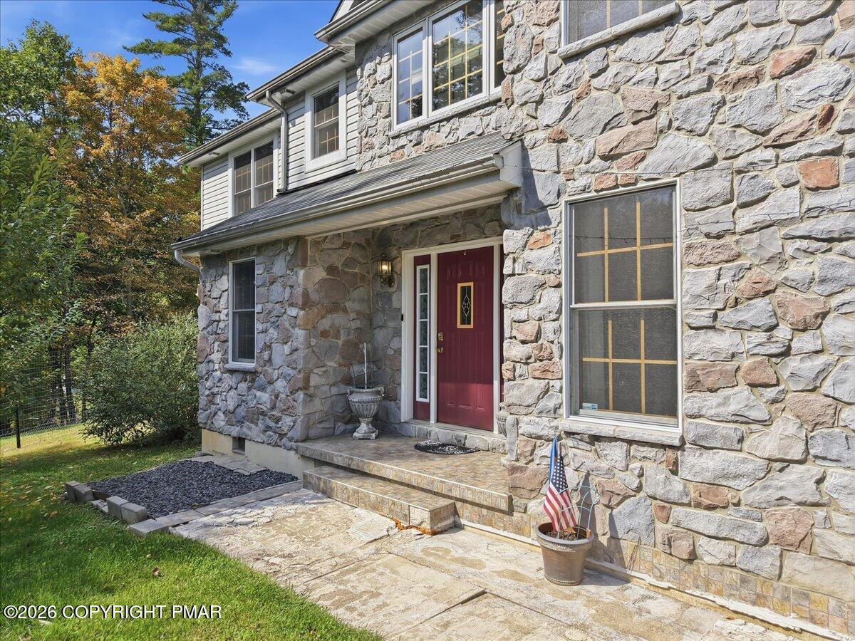 Stone-faced home with a red front door, stone entry steps, and a flag by the patio.
