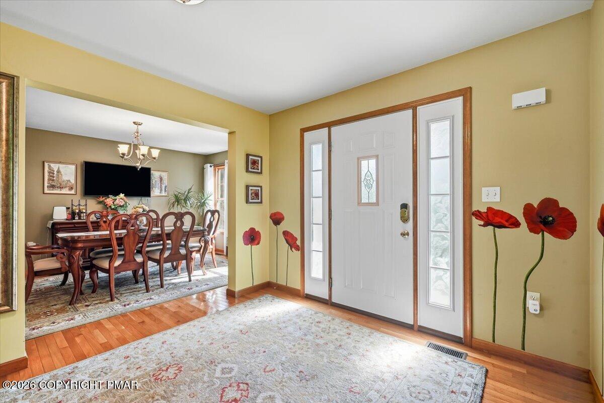 Home entry with a white glass-paneled front door, hardwood floors, and an adjoining dining room.