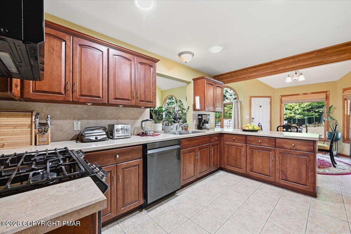 Kitchen with reddish-brown wood cabinetry, a gas cooktop, and a raised wood ceiling beam.