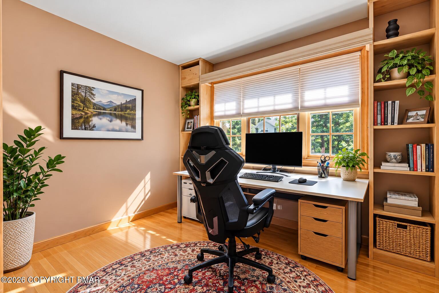 Home office with built-in wood shelving, a large window, and a desk with computer.