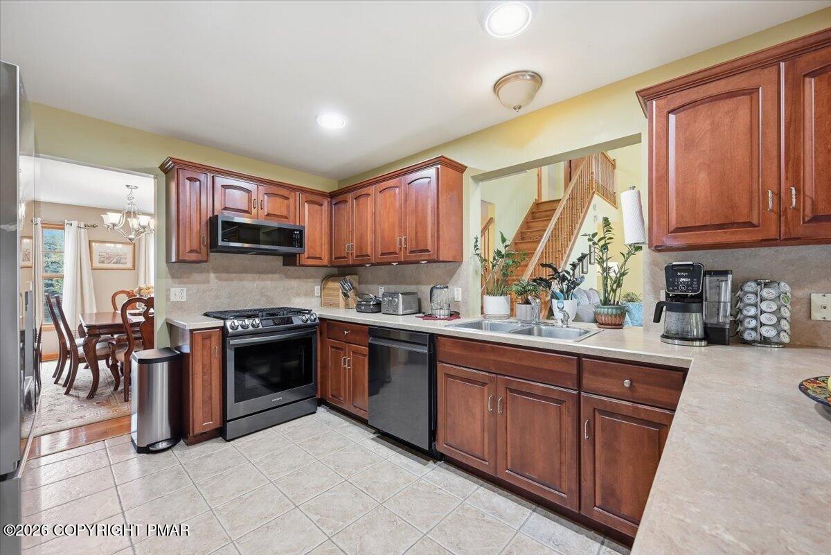 Kitchen with rich wood cabinetry, stainless steel appliances, and a view toward the staircase.