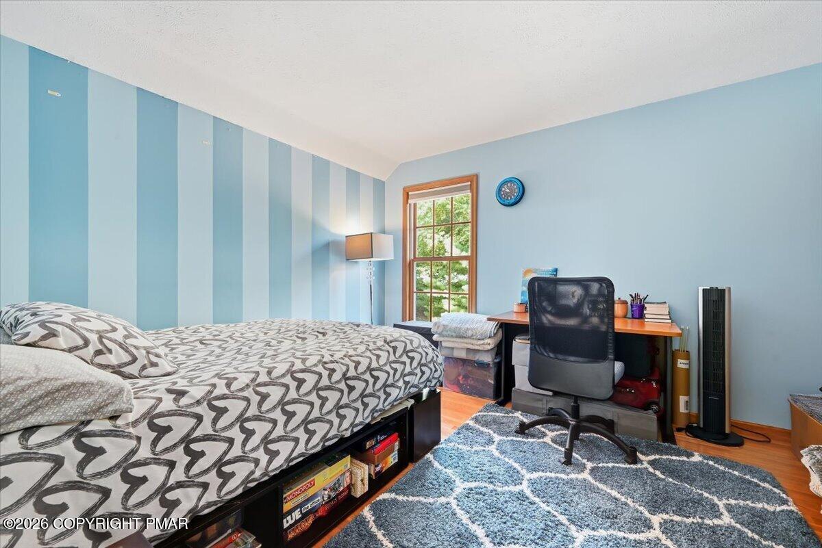 Bedroom office with heart-patterned bedding, a desk by the window, and blue striped walls.