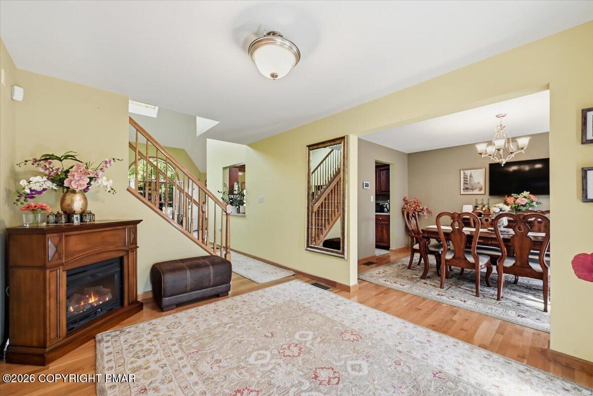 Living room with a fireplace, hardwood floors, and an open view into the dining area.
