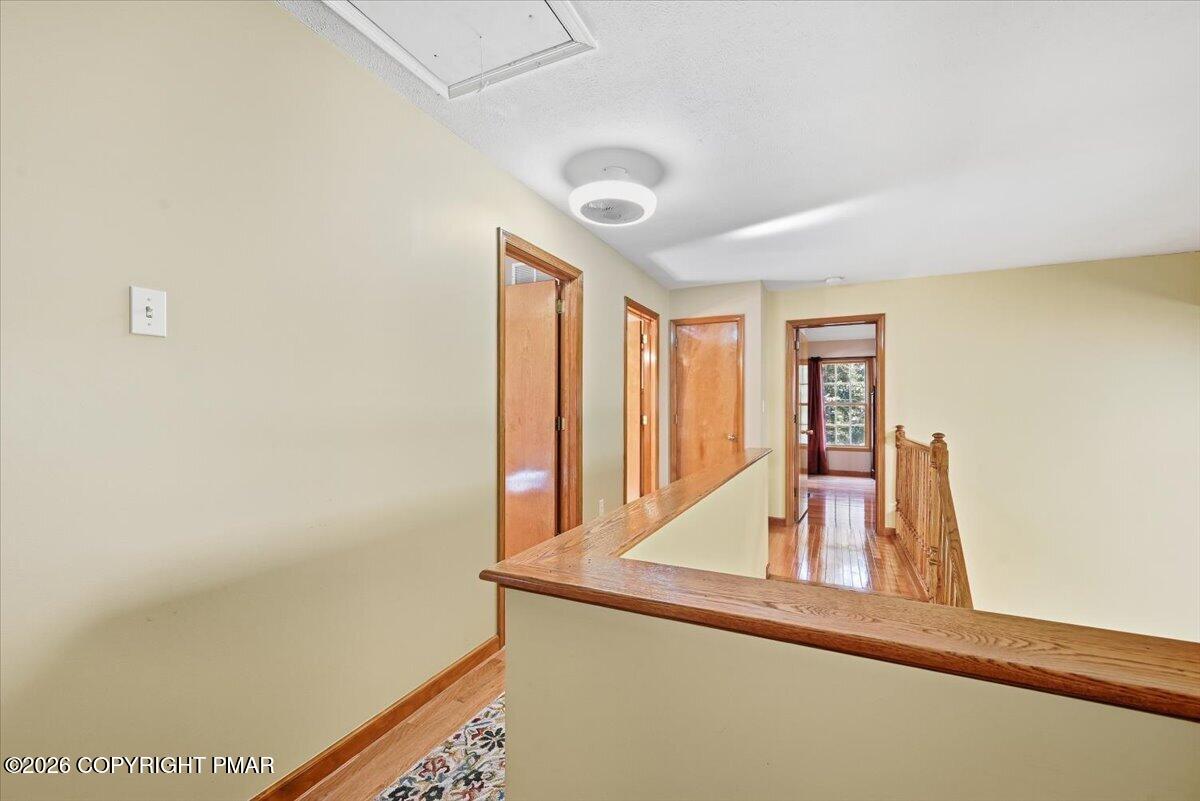 Upstairs hallway with polished hardwood floors, wood-trimmed doorways, and a wooden stair railing.